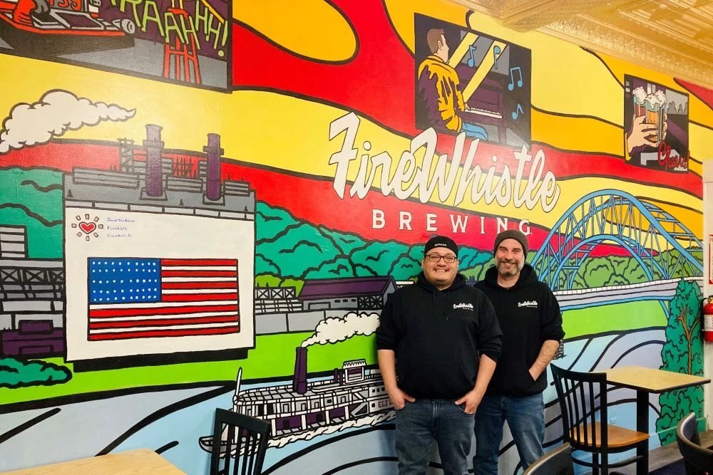 Firewhistle Brewing owners at the taproom mural